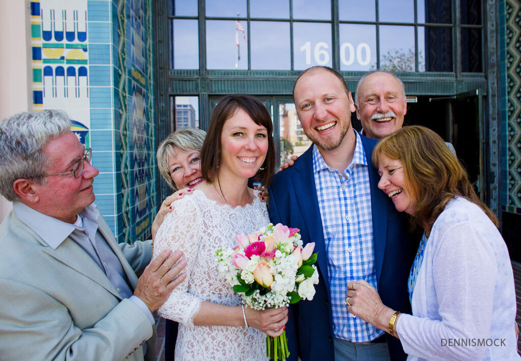 wedding couple receives congrats and hugs from loving parents outside the San Diego courthouse