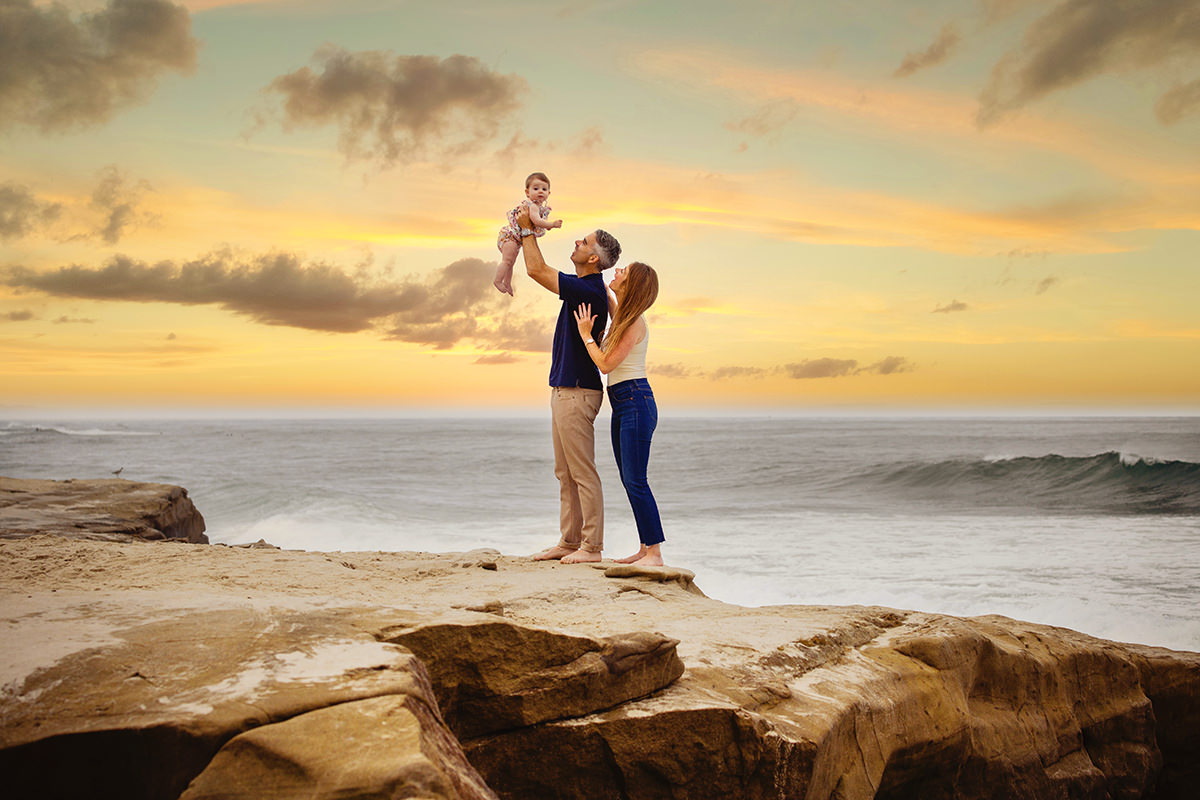 Best place for family portraits at sunset in San Diego. Pictured is child, mom and dad having fun 